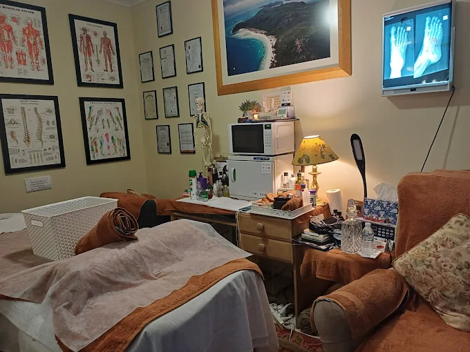 Professional massage therapy clinic interior showing treatment room with anatomical charts, massage table, and therapeutic equipment at Restoration Myotherapy and Reflexology in Bald Hills